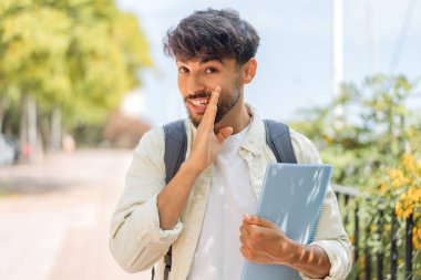 Genç bir Arap öğrenci açık havada bir şeyler fısıldıyor.