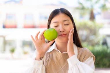 Dışarıdaki güzel Çinli kadın elinde elma tutuyor.
