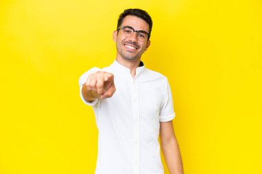 Soyutlanmış sarı arka planda genç yakışıklı adam mutlu bir ifadeyle öne bakıyor.