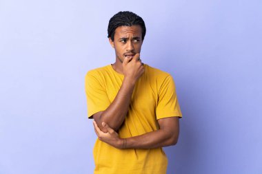 Örgülü genç Afrikalı Amerikalı adam mor arka planda izole edilmiş gergin ve korkmuş.