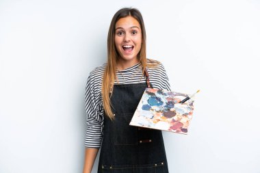 Beyaz arka planda beyaz bir palet tutan beyaz bir kadın. Şaşırtıcı bir yüz ifadesi.