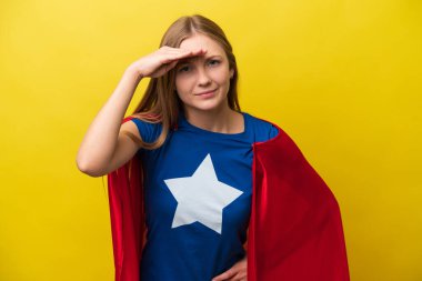 Genç Rus kadın sarı arka planda, süper kahraman kostümüyle izole edilmiş ve bir şeyler gösteriyor.