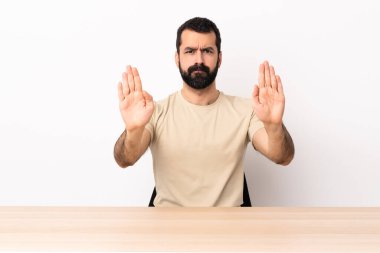 Masada sakallı beyaz bir adam dur hareketi yapıyor ve hayal kırıklığına uğruyor..