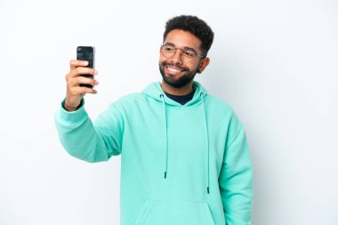 Beyaz arka planda izole edilmiş genç Brezilyalı bir adam selfie çekiyor.