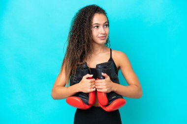 Genç Arap kadın mavi arka planda boks eldivenleriyle izole edilmiş.