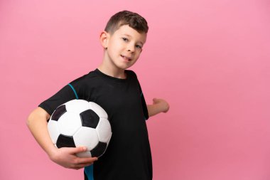 Küçük beyaz futbolcu çocuk pembe arka planda izole edilmiş. Gelmesi için ellerini yana uzatıyor.