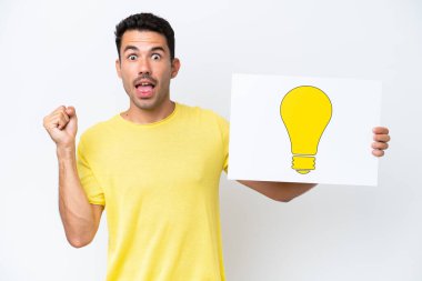 Soyutlanmış beyaz arka planda genç yakışıklı bir adam elinde ampul simgesiyle bir pankart tutuyor ve zaferi kutluyor.