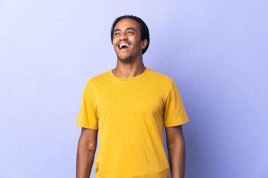 Örgülü genç Afrikalı Amerikalı adam, mor arka planda izole edilmiş gülüyor.
