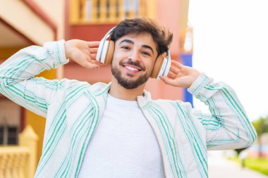 Açık havada müzik dinleyen yakışıklı bir Arap.