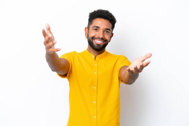 Beyaz arka planda izole edilmiş genç Brezilyalı adam sunar ve davet eder.