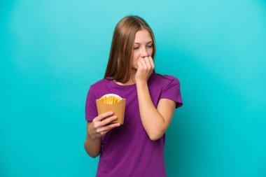 Kızarmış patates yiyen genç Rus kadın mavi arka planda izole edilmiş şüpheleri var.
