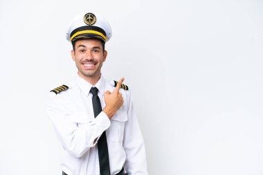 İzole edilmiş beyaz arka plan üzerinde uçak pilotu bir ürünü sunmak için kenarı işaret ediyor