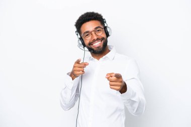 Tele pazarlamacı Brezilyalı bir adam beyaz arka planda izole edilmiş bir kulaklıkla çalışıyor. Önü işaret ediyor ve gülümsüyor.