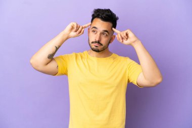 Mor arka planda soyutlanmış genç beyaz bir adamın şüpheleri ve düşünceleri var.