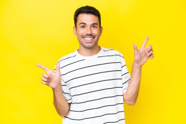 Soyutlanmış sarı arka planda genç yakışıklı adam parmak ucunda ve mutlu.