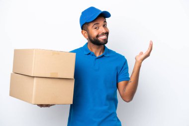 Teslimat yapan Brezilyalı adam beyaz arka planda izole edilmiş. Davet etmek için ellerini yana uzatıyor.