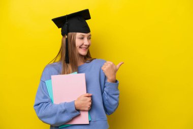 Sarı arka planda izole edilmiş genç bayan bir ürün sunmak için kenarı işaret ediyor.