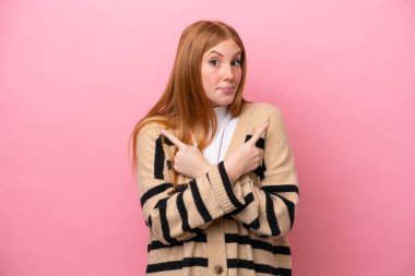 Genç kızıl saçlı kadın pembe arka planda izole edilmiş. Yan taraftakilerin şüpheleri olduğunu gösteriyor.