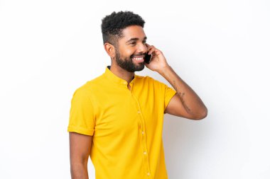 Genç Brezilyalı adam beyaz arka planda izole edilmiş cep telefonuyla sohbet ediyor.