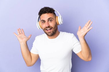 Mor arka planda izole edilmiş beyaz adam şaşırdı ve müzik dinliyor.