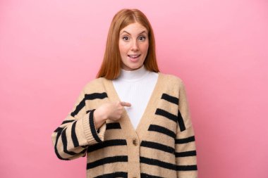 Genç kızıl saçlı kadın pembe arka planda izole edilmiş ve yüzünde sürpriz bir ifade var.