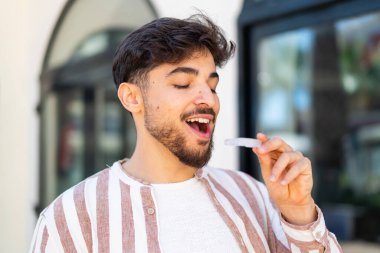 Dışarıdaki yakışıklı Arap adam görünmez diş telleri tutuyor.