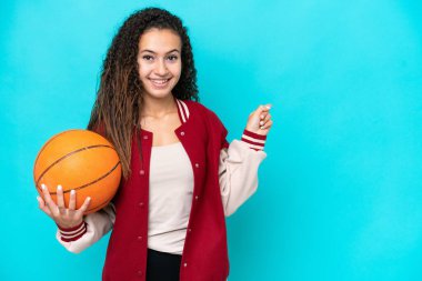 Arap basketbolcu kadın, mavi arka planda izole edilmiş, parmak kenarı işaret ediyor.