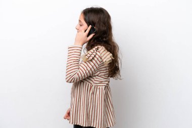 Beyaz arka planda izole edilmiş küçük bir kız cep telefonuyla biriyle sohbet ediyor.