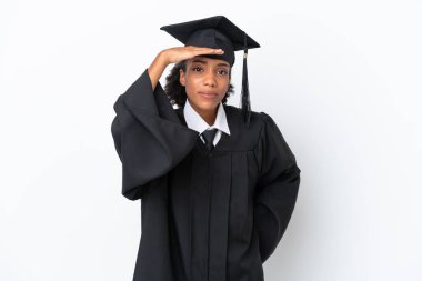 Genç üniversite mezunu Afro-Amerikalı bir kadın beyaz arka planda izole edilmiş bir şekilde bir şeye bakmak için uzaklara bakıyor.