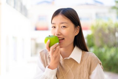 Dışarıdaki güzel Çinli kadın elinde elma tutuyor.