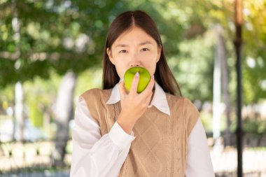 Dışarıdaki güzel Çinli kadın elma yiyor.