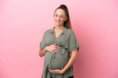 Pembe arka planda izole genç bir kadın hamile ve mutlu.