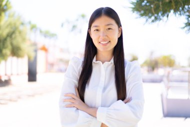 Dışarıdaki güzel Çinli kadın kollarını ön cephede çapraz tutuyor.