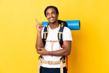 Sarı arka planda büyük bir sırt çantası olan genç dağcı harika bir fikre işaret ediyor.