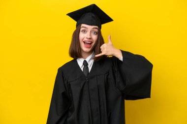 Ukraynalı genç bir üniversite mezunu sarı arka planda izole edilmiş telefon jesti yapıyor. Bana geri dönüş işareti ver.