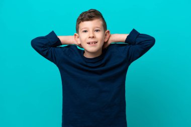 Küçük çocuk mavi arka planda yalnız gülüyor.