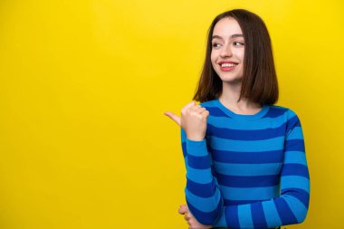 Young Ukrainian woman isolated on yellow background pointing to the side to present a product