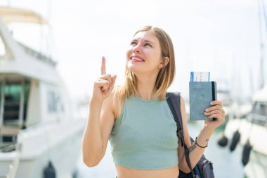 Dışarıda pasaportu olan genç sarışın kadın parmağını kaldırarak çözümü bulmaya çalışıyor.