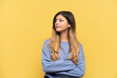 Sarı arka planda izole edilmiş genç Rus kız yan tarafa bakıyor.