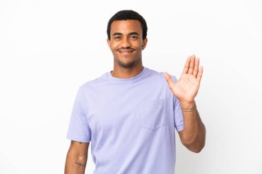 Afro-Amerikalı yakışıklı adam izole edilmiş beyaz arka planda mutlu bir ifadeyle selamlıyor.