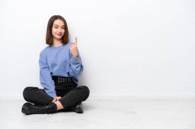 Genç Ukraynalı kadın beyaz arka planda izole bir şekilde yerde oturuyor işaret parmağıyla işaret etmek harika bir fikir.