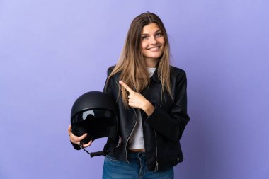 Mor arka planda motosiklet kaskı tutan genç Slovak kadın bir ürünü sunmak için yan tarafa bakıyor.