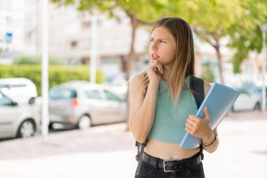 Açık havada genç sarışın bir bayan bir fikir üretiyor ve ona bakıyor.