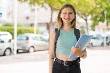 Açık havada gülümseyen sarışın genç bayan.