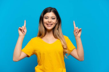 Mavi arka planda izole edilmiş genç Rus kız harika bir fikre işaret ediyor.