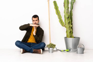 Bahçıvan içeride yerde oturuyor. Mola jesti yapıyor.