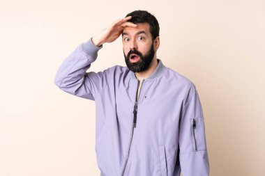 Sakallı beyaz bir adam, izole edilmiş arka planda ceket giyiyor. Yan tarafa bakarken sürpriz jest yapıyor.