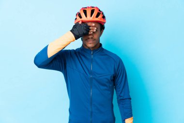 İzole edilmiş arka planda örgü ören bisikletli genç bir adam gözleri elleriyle kapatıyor. Bir şey görmek istemiyorum.