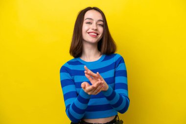 Sarı arka planda izole edilmiş genç Ukraynalı kadın bir konferansta sunumdan sonra alkışlıyor.