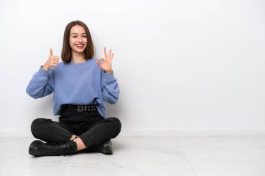 Genç Ukraynalı bir kadın beyaz arka planda izole bir şekilde yerde oturuyor.